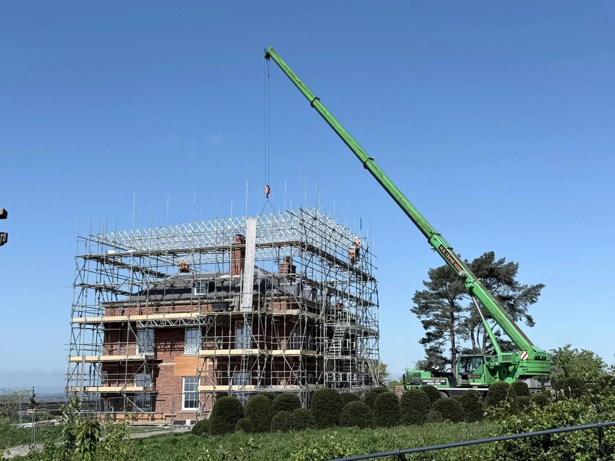M.R. Crane Hire crane at work beside a scaffolded building